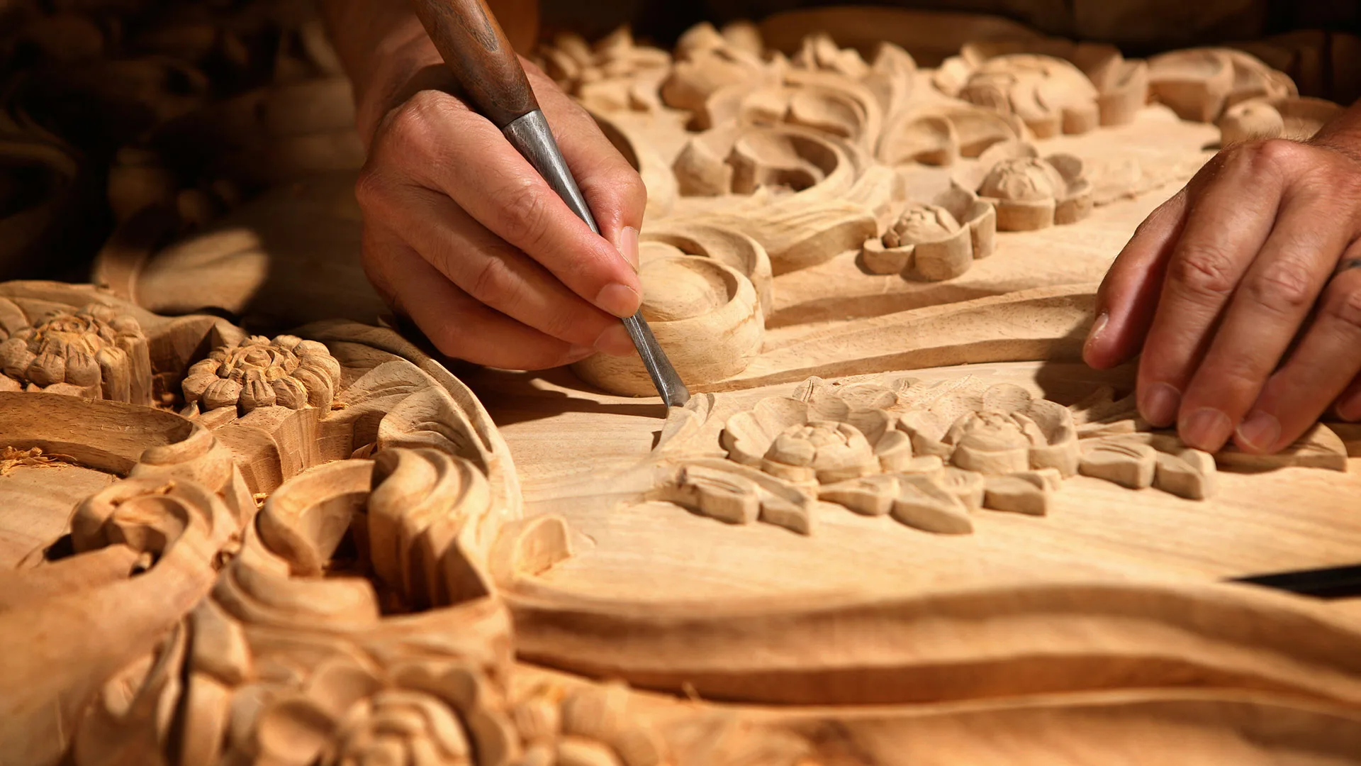 Craftsperson carving traditional motifs into wood