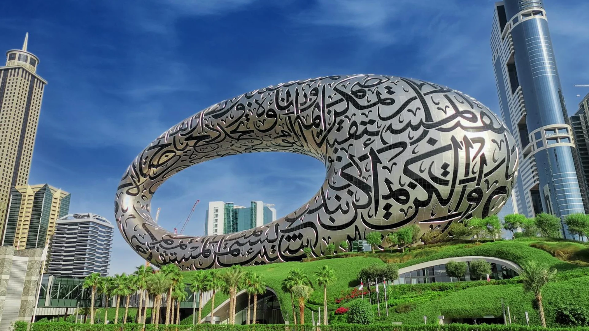 People strolling along a sculpture walk beside modern buildings