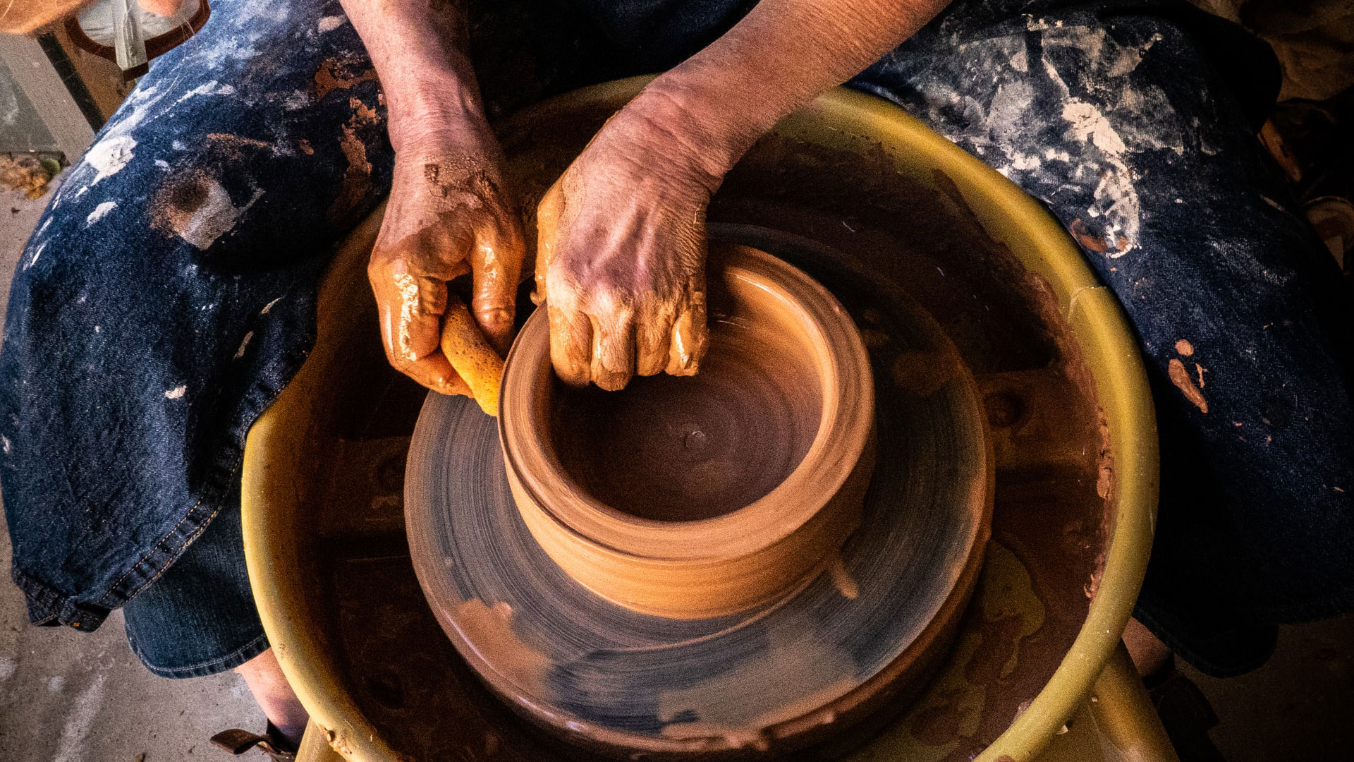 Potter shaping clay vessel in a heritage studio